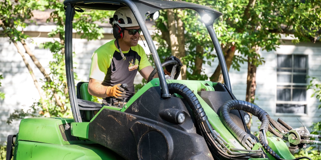 Outdoor business owner in branded Monster Tree uniform driving equipment.